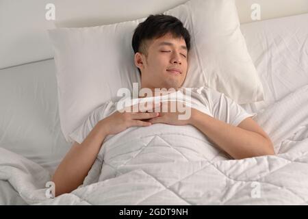 Handsome Young Asian man sleeping in bed Stock Photo