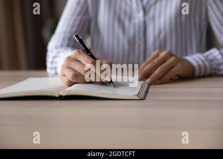 Close up of woman writing in stationary notepad Stock Photo