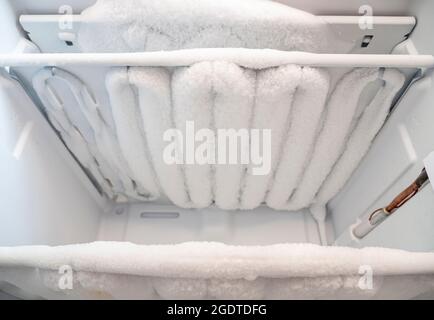 Close-up of opened deep freezer with ice and snow. Freezer before defrost. Empty shelves of fridge. Stock Photo