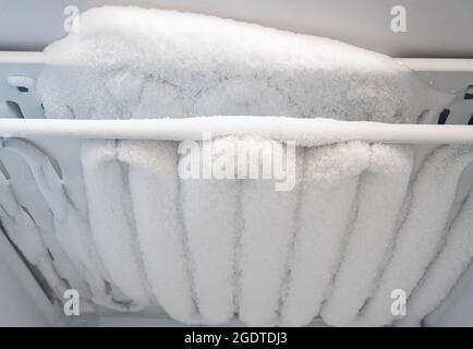 Close-up of opened deep freezer with ice and snow. Freezer before defrost. Empty shelves of fridge. Stock Photo