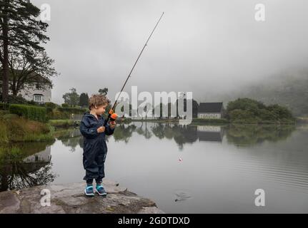 Gougane Barra, Cork, Ireland. 14th August, 2021. On a misty day in West Cork a four year old boy tries out his new toy fishing rod on the lake at Gougane Barra, Co. Cork, Ireland. - Picture; David Creedon / Alamy Live News Stock Photo