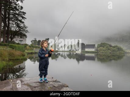 Gougane Barra, Cork, Ireland. 14th August, 2021. On a misty day in West Cork a four year old boy tries out his new toy fishing rod on the lake at Gougane Barra, Co. Cork, Ireland. - Picture; David Creedon / Alamy Live News Stock Photo