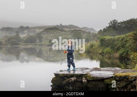 Gougane Barra, Cork, Ireland. 14th August, 2021. On a misty day in West Cork a four year old boy tries out his new toy fishing rod on the lake at Gougane Barra, Co. Cork, Ireland. - Picture; David Creedon / Alamy Live News Stock Photo