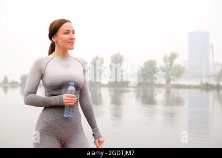 Woman dressed leggings and top with pink mat doing yoga on summer outdoor. Healthy sport lifestyle concept. Active and athletic female exercises Stock Photo