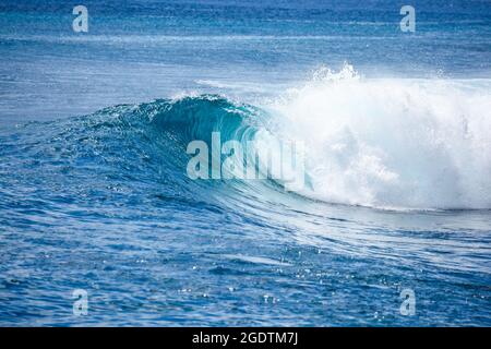 A wave breaks unridden on a shallow coral reef in the Mentawai Islands - Indonesia. The Mentawai's have some of the best waves in the world. Stock Photo