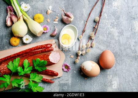 Sausage decorated with parsley leaves, onion, eggs and catkins.  Breakfast time Stock Photo