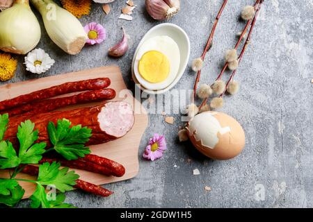 Sausage decorated with parsley leaves, onion, eggs and catkins.  Breakfast time Stock Photo