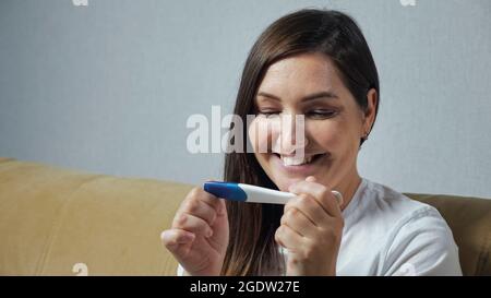 Close-up of young woman happily looking at pregnancy test Stock Photo