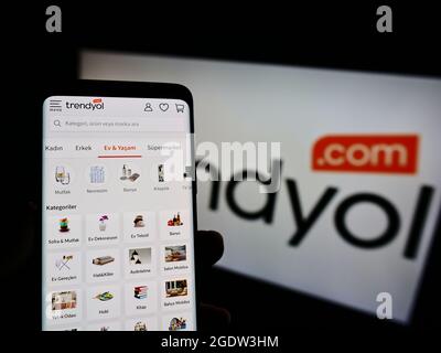 Person holding cellphone with webpage of Turkish e-commerce company Trendyol on screen in front of business logo. Focus on center of phone display. Stock Photo