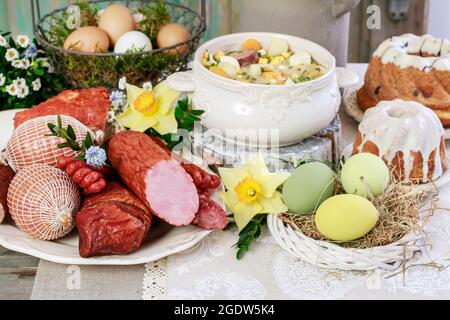 The sour rye soup, easter cakes and saussages on the table. Festive breakfast Stock Photo
