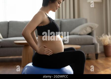 Happy young pregnant woman doing exercises with fitball at home Stock Photo
