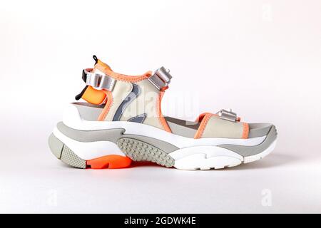 Women's, fashionable, sports sandals with orange accents on a white background. New youth shoes for girls. Side view Stock Photo