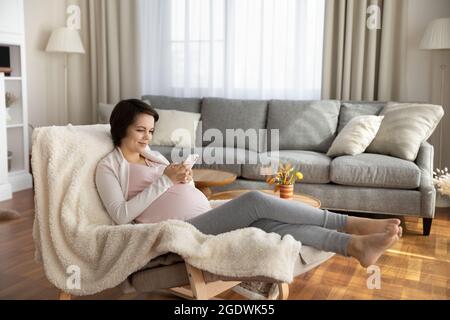 Happy satisfied young pregnant woman shopping online from home Stock Photo