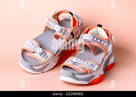 Women's, fashionable, sports sandals with orange accents on a pink background. New youth shoes for girls. Front view. Stock Photo