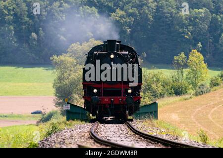 Streitberg, Germany. 15th Aug, 2021. A historic steam locomotive passes Streitberg in Franconian Switzerland. The locomotive is a passenger train tender with the number 64 491 that was built in 1940 by the manufacturer 'Orenstein & Koppel' in Berlin. According to the homepage of the 'Dampfbahn Fränkische Schweiz e.V.', the locomotive was taken out of service in Crailsheim in 1974 as one of the last of its class at the Deutsche Bahn (DB) and was also used for film productions such as 'Unsere Mütter, unsere Väter'. Credit: Nicolas Armer/dpa/Alamy Live News Stock Photo