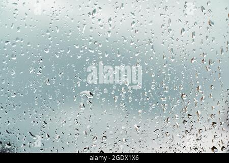 Rain drops on window glasses surface blurred cloudy background Stock Photo