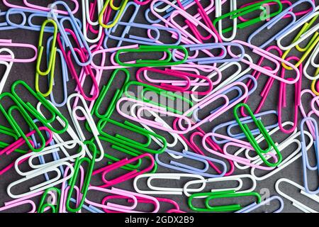 Multicolored paper clips scattered as textured background in full screen Stock Photo