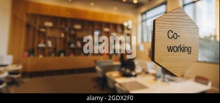 Co-working writing on wooden plate over a glass partition. Open plan office space for coworking. Stock Photo
