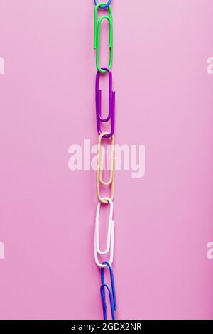 Multicolored paper clips are attached in a row on a pink background. Free space Stock Photo