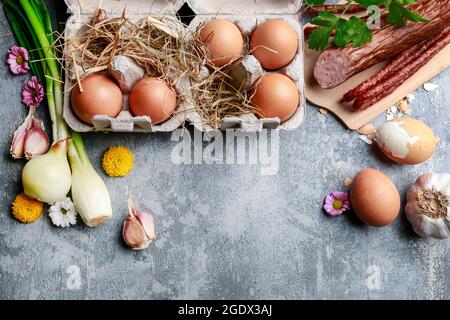 Eggs, bread, smoked sausage and vegetables. Easter food on grey, stone backround. Festive dishes Stock Photo