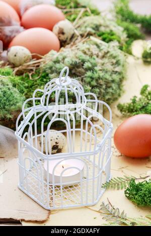 Vintage bird cage with candle, moss and Easter eggs around. Festive time Stock Photo