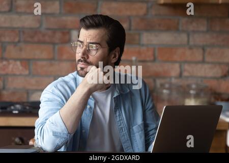 Pensive young man work on laptop thinking Stock Photo