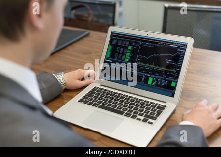 Young businessman working with laptop, man's hands on notebook computer. Stock Photo