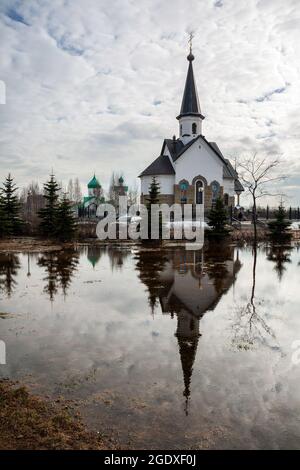 Church of St. George the Victorious on Srednaya Rogatka (Middle Slingshot) is reflected in a huge pool of melt water in early spring. Pulkovo Park in Stock Photo