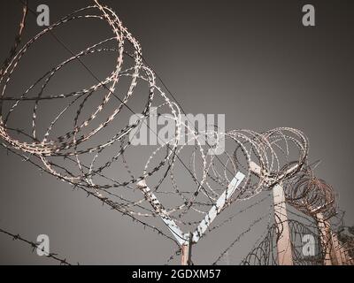 Barbed wire against dark grey sky Stock Photo