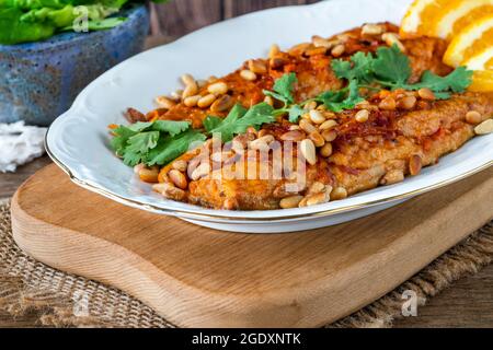 Mackerel fillets with orange and harissa glaze, green leaf salad and roasted pine nuts Stock Photo