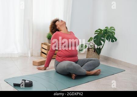 African senior woman doing yoga exercises at home - Training and healthy lifestyle - Focus on face Stock Photo