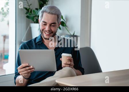 Young business man working inside coworking office while drinking coffee - Focus on face Stock Photo