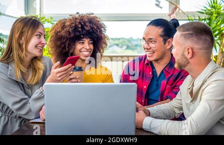 group of young adult students having a break during home work. multicultural happy people working in start up coworking space discussing a project. Stock Photo