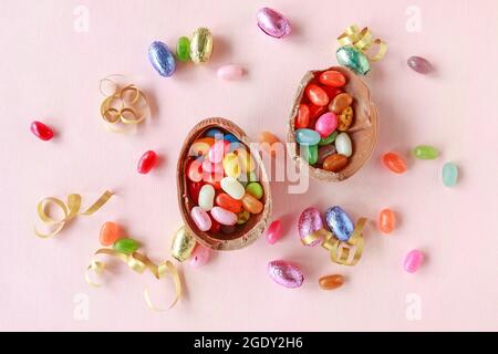 Chocolate Easter eggs and other sweets on pink background. Festive time Stock Photo