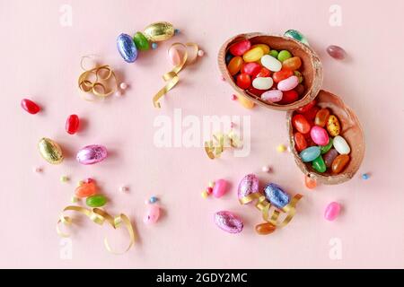 Chocolate Easter eggs and other sweets on pink background. Festive time Stock Photo