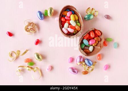 Chocolate Easter eggs and other sweets on pink background. Festive time Stock Photo