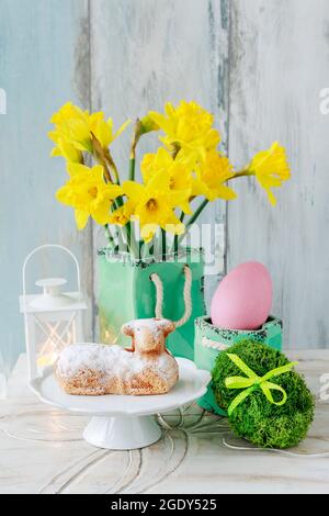 Easter table with lamb cake, bouquet of daffodils and painted eggs. Festive decor Stock Photo