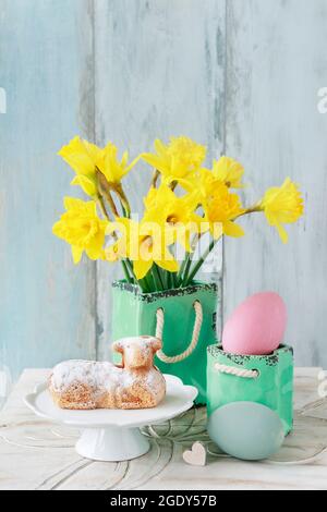 Easter table with lamb cake, bouquet of daffodils and painted eggs. Festive decor Stock Photo