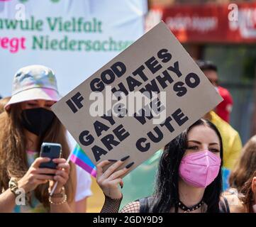 Braunschweig, Germany, August 14, 2021: Young homosexual man holding a poster saying if God hates Gay why are we so cute at CSD Christopher Street day Stock Photo