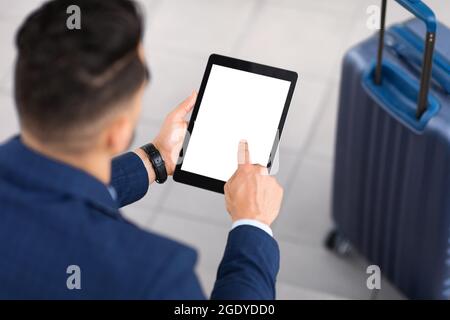 Man Using Digital Tablet With Blank Screen While Sitting With Luggage Outdoors Stock Photo