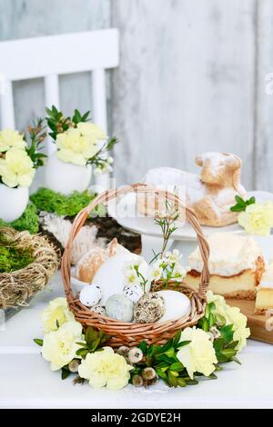 Easter basket with eggs decorated with wreath made of carnations, buxus and catkins. Spring decor Stock Photo