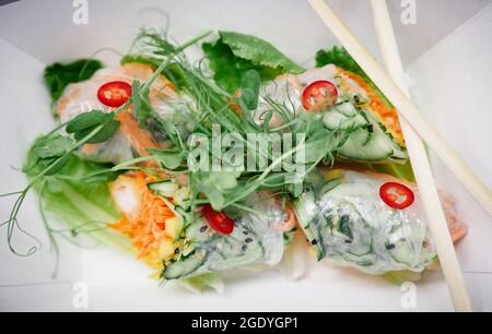 Closeup multicolor fresh vegetables spring roll as asian fast food. Vietnamese spring rolls with microgreen, carrot, cucumber and shrimps in tempura. Vegan healthy food concept. High quality photo Stock Photo