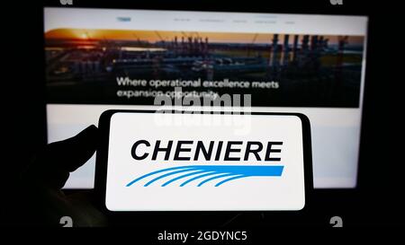 Person holding smartphone with logo of US LNG company Cheniere Energy Inc. on screen in front of website. Focus on phone display. Stock Photo