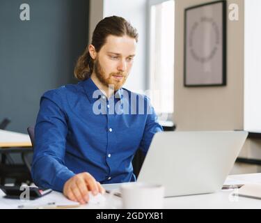 Young focused man freelancer working on laptop computer remotely Stock Photo