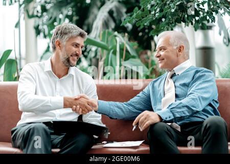 financial partners confidently shaking hands with each other . Stock Photo