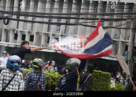 Bangkok, Thailand. 01st Jan, 2000. A protester holds a fire cracker onto the Thailand flag, during clashes. Thai anti-government protesters clashed with police as they demonstrated against government's failure to handle the coronavirus outbreaks. Credit: SOPA Images Limited/Alamy Live News Stock Photo