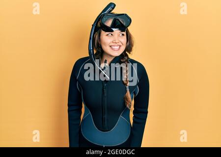 Young hispanic girl wearing diver neoprene uniform looking to side, relax profile pose with natural face and confident smile. Stock Photo