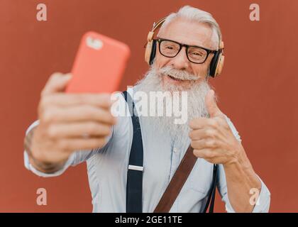 older man makes video call with his smartphone while indicating that it is all right Stock Photo