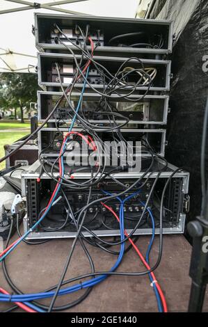 Cabling in multiple flight case racks with amplifier, effect devices, and radio microphone system on the desk of the sound mixer an open air music fes Stock Photo