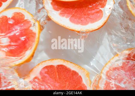 Close-up fresh slices of red grapefruit on white background. Slices of grapefruit in sparkling water on white background, closeup. Citrus soda. Copy Stock Photo